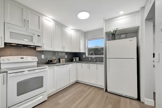 kitchen featuring white appliances, white cabinetry, sink, backsplash, and light wood-type flooring