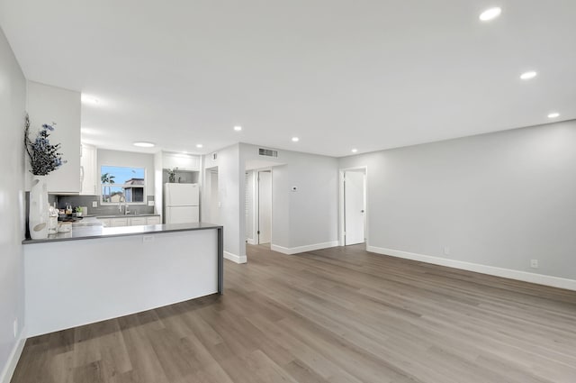 kitchen featuring white cabinets, wood-type flooring, white fridge, sink, and kitchen peninsula