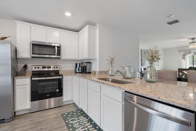 kitchen with stainless steel appliances, ceiling fan, sink, light hardwood / wood-style flooring, and white cabinetry