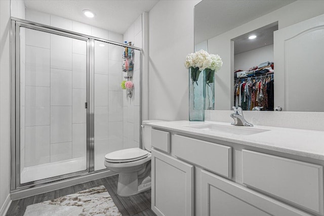 bathroom featuring toilet, a shower with door, and vanity