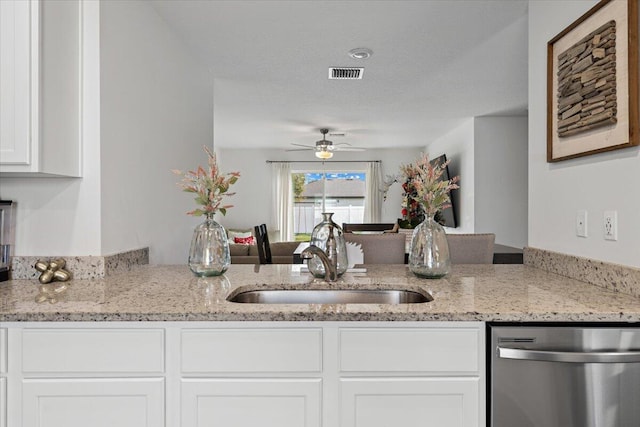 kitchen with sink, white cabinets, dishwasher, light stone counters, and ceiling fan