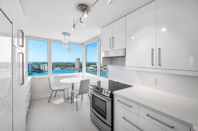 kitchen with light tile patterned floors, white cabinets, pendant lighting, electric stove, and a water view