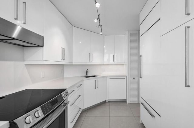 kitchen featuring track lighting, sink, light tile patterned floors, electric range oven, and white cabinetry