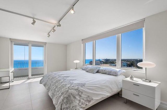 bedroom featuring access to exterior, track lighting, a water view, and multiple windows