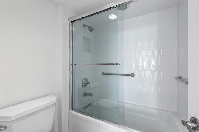 bathroom with toilet and bath / shower combo with glass door