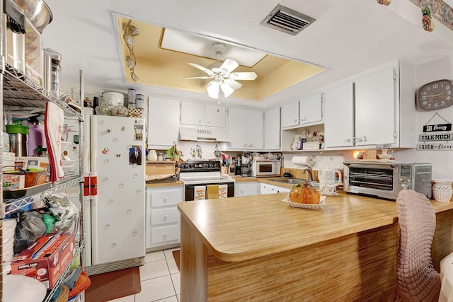 kitchen with custom range hood, white appliances, white cabinetry, and a raised ceiling