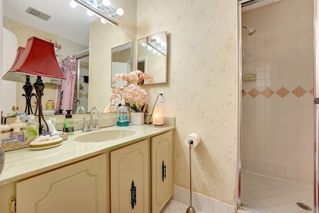 bathroom with tile patterned floors, vanity, and tiled shower