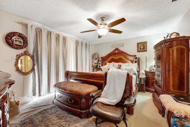 bedroom with ceiling fan, light colored carpet, and a textured ceiling