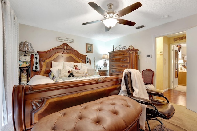 bedroom with a textured ceiling, ensuite bathroom, and ceiling fan