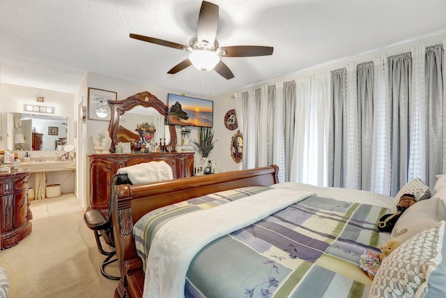 carpeted bedroom featuring ceiling fan, a textured ceiling, and ensuite bath