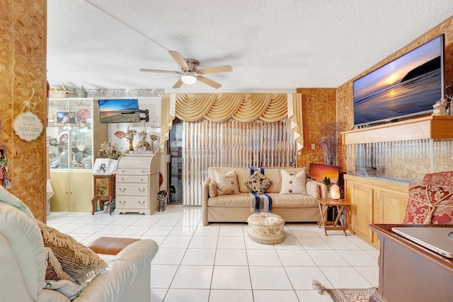 living room with ceiling fan, light tile patterned floors, and a textured ceiling