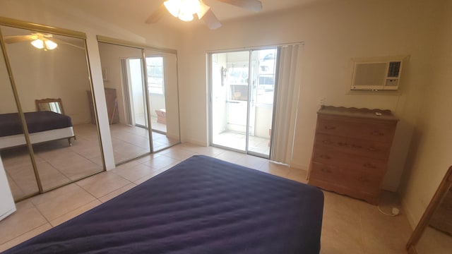 tiled bedroom featuring a wall unit AC, ceiling fan, and multiple closets