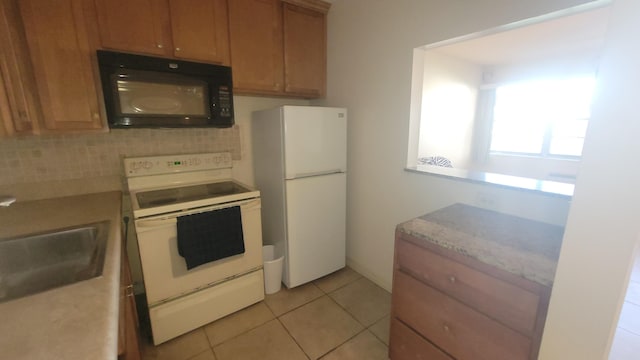 kitchen featuring tasteful backsplash, sink, light tile patterned floors, and white appliances