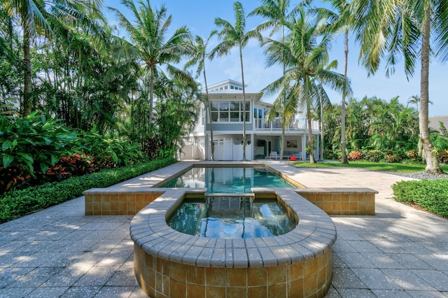 rear view of property featuring a swimming pool with hot tub and a patio