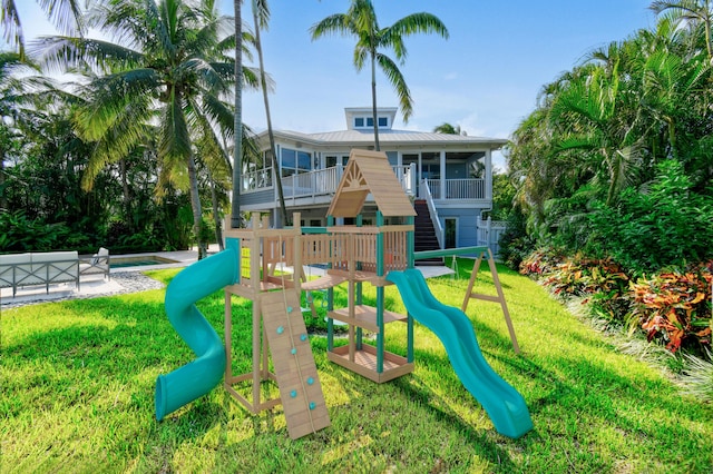 view of playground featuring a pool, a yard, and a sunroom