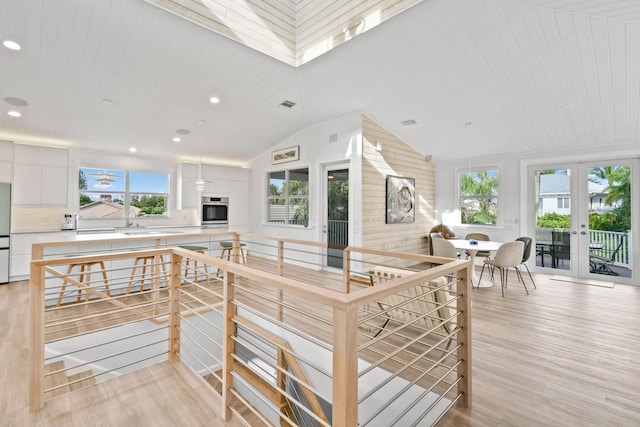 kitchen with french doors, lofted ceiling, white cabinets, and oven