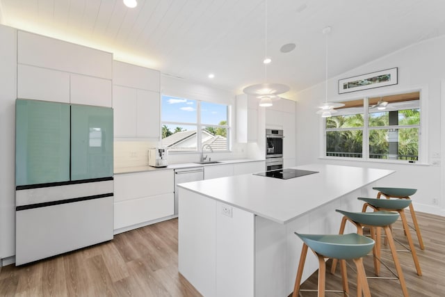 kitchen featuring tasteful backsplash, lofted ceiling, refrigerator, a kitchen island, and white cabinets