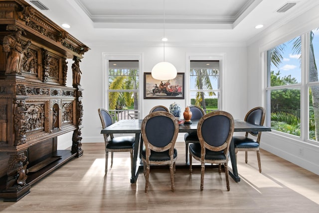 dining space with light hardwood / wood-style floors, crown molding, and a raised ceiling