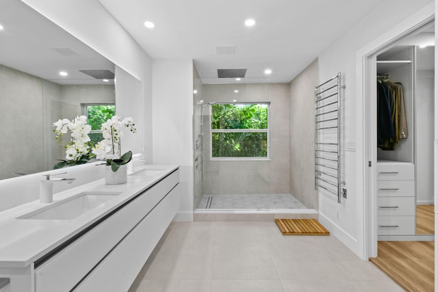 bathroom featuring vanity, a tile shower, and tile patterned flooring