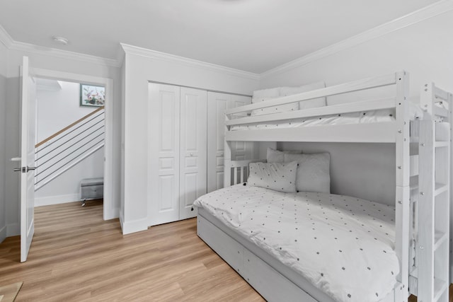 bedroom with a closet, ornamental molding, and light hardwood / wood-style flooring