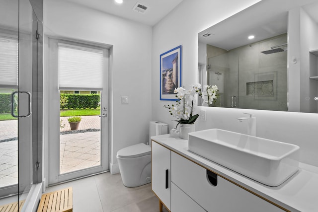 bathroom with toilet, vanity, a shower with door, and tile patterned floors