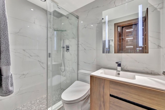 bathroom featuring a shower with door, vanity, tile walls, and toilet