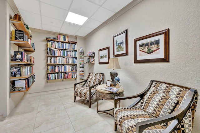 living area featuring a paneled ceiling, light tile patterned flooring, and ornamental molding