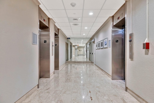 hall with a paneled ceiling and elevator