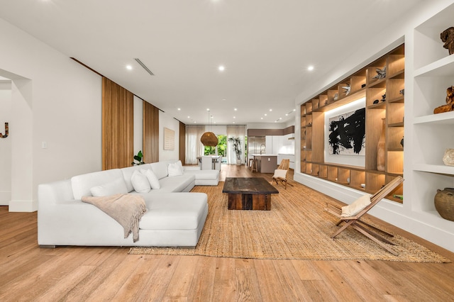 living room with built in shelves and light hardwood / wood-style flooring