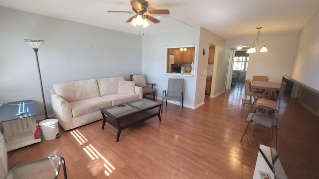 living room featuring ceiling fan with notable chandelier and hardwood / wood-style flooring