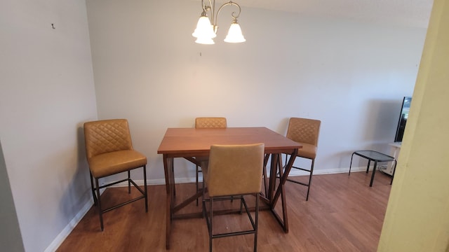 dining area with wood-type flooring and an inviting chandelier