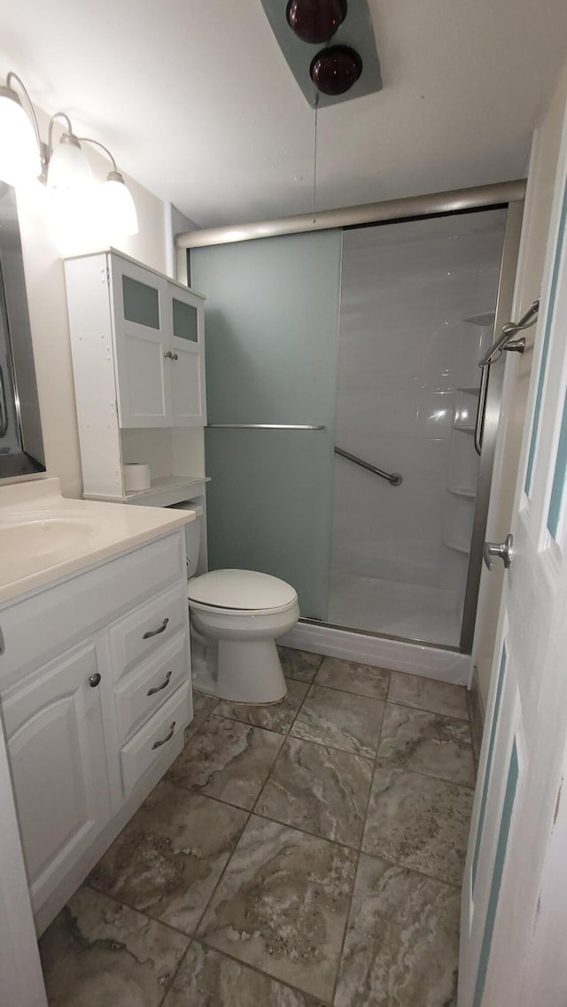 bathroom with a shower with door, vanity, and toilet