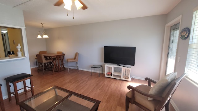 living room with hardwood / wood-style floors and ceiling fan with notable chandelier