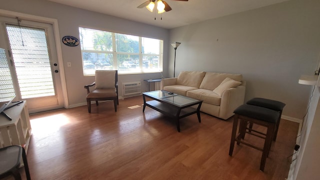 living room featuring wood-type flooring, a wall mounted AC, and ceiling fan