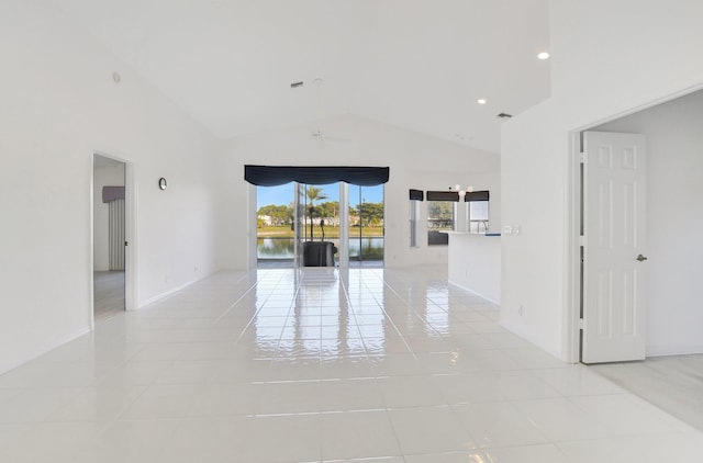 spare room with a water view, light tile patterned floors, and high vaulted ceiling