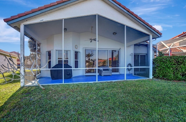 rear view of property with ceiling fan and a yard