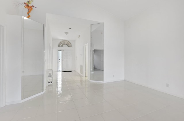 unfurnished room with light tile patterned flooring and vaulted ceiling