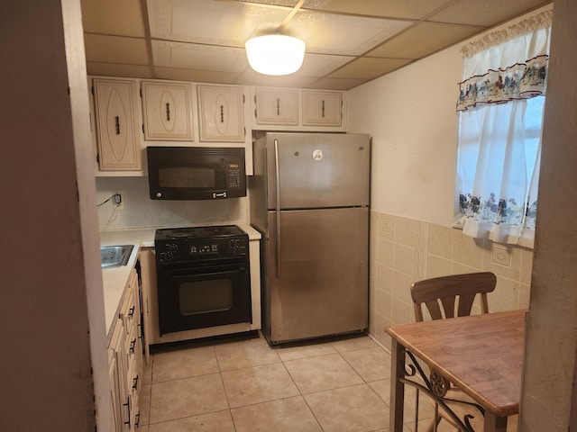 kitchen featuring tile walls, light tile patterned floors, black appliances, and a drop ceiling