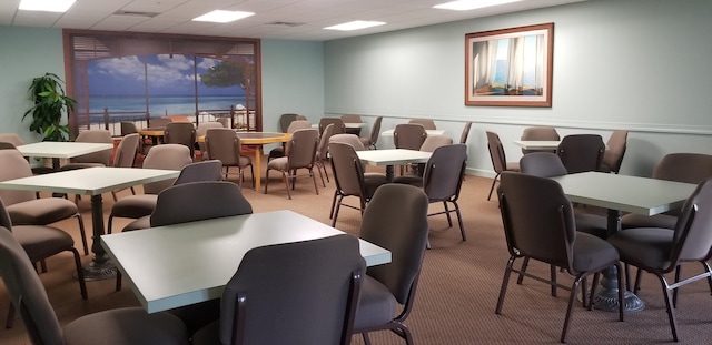 dining room featuring a drop ceiling and light colored carpet