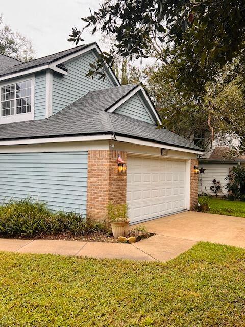 view of side of property featuring a garage and a lawn