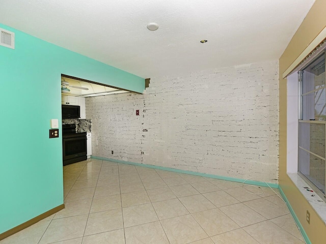 tiled spare room featuring brick wall