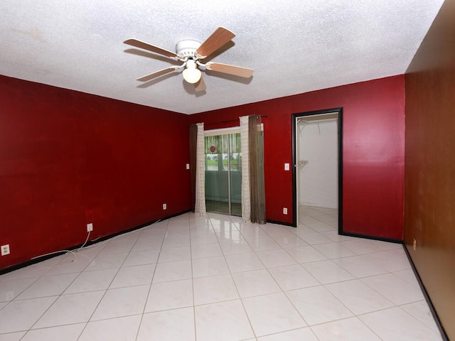 tiled empty room featuring a textured ceiling and ceiling fan