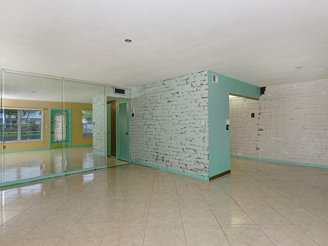 tiled spare room with brick wall