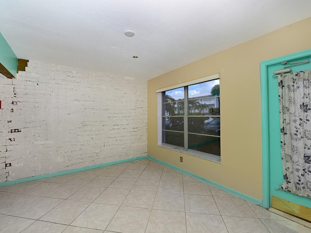 tiled spare room with brick wall