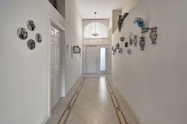 entryway featuring a notable chandelier, light tile patterned floors, and a high ceiling