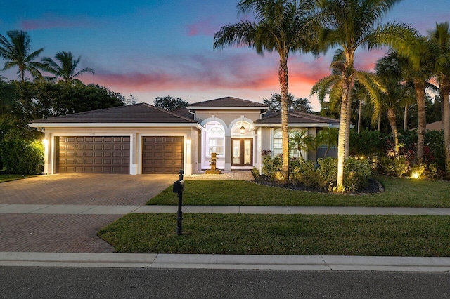 mediterranean / spanish-style home with a yard, french doors, and a garage