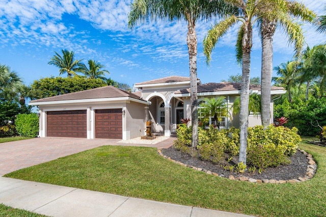 mediterranean / spanish house with a garage and a front lawn