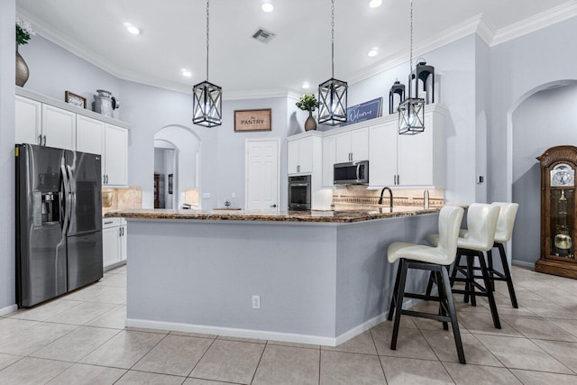 kitchen with stainless steel appliances, light tile patterned floors, dark stone countertops, decorative backsplash, and white cabinets