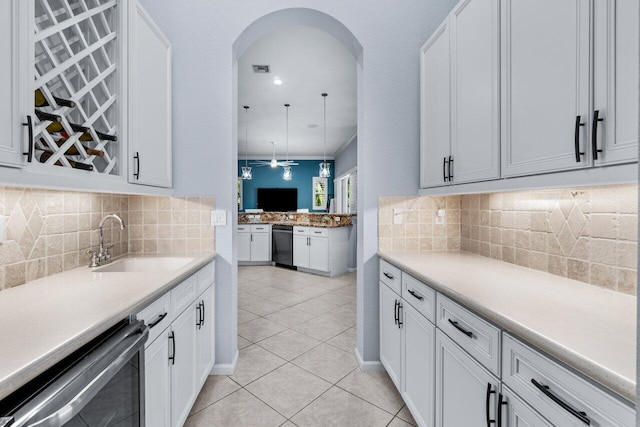 kitchen featuring sink, dishwashing machine, hanging light fixtures, decorative backsplash, and white cabinets