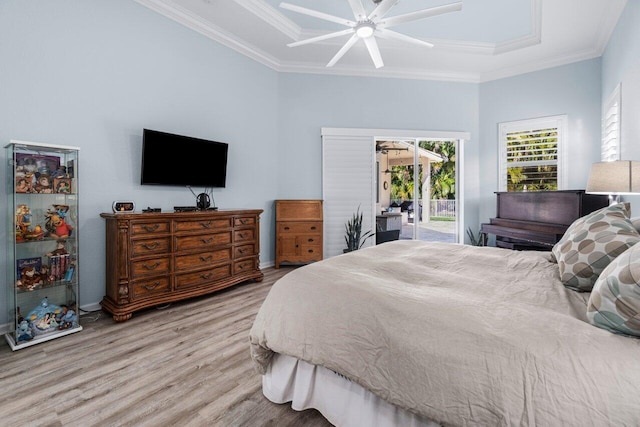 bedroom featuring light wood-type flooring, ornamental molding, access to outside, a tray ceiling, and ceiling fan